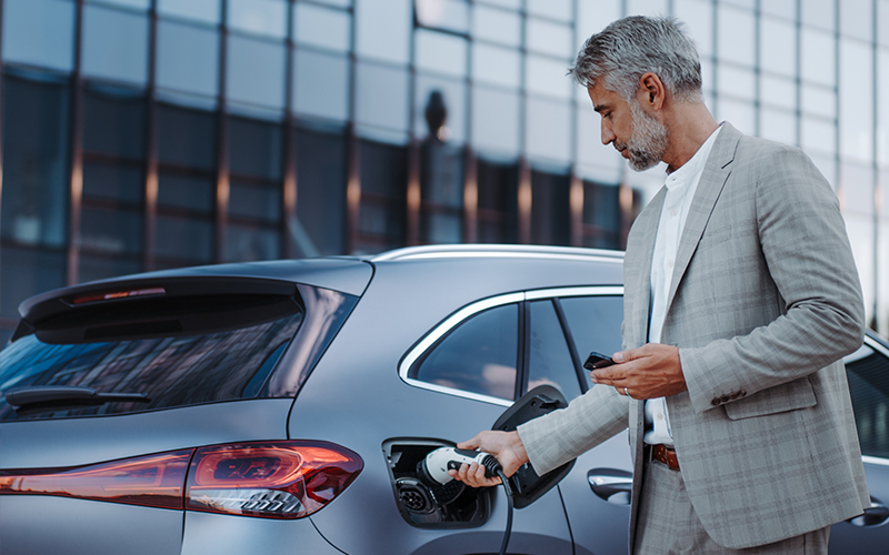 Ein Mann in grauem Anzug lädt sein E-Auto